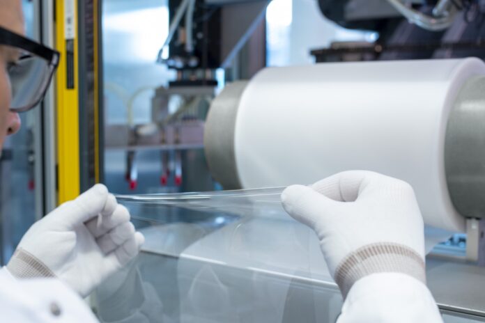 Elongation of a transparent, ultra-thin plastic film pulled from a roll.